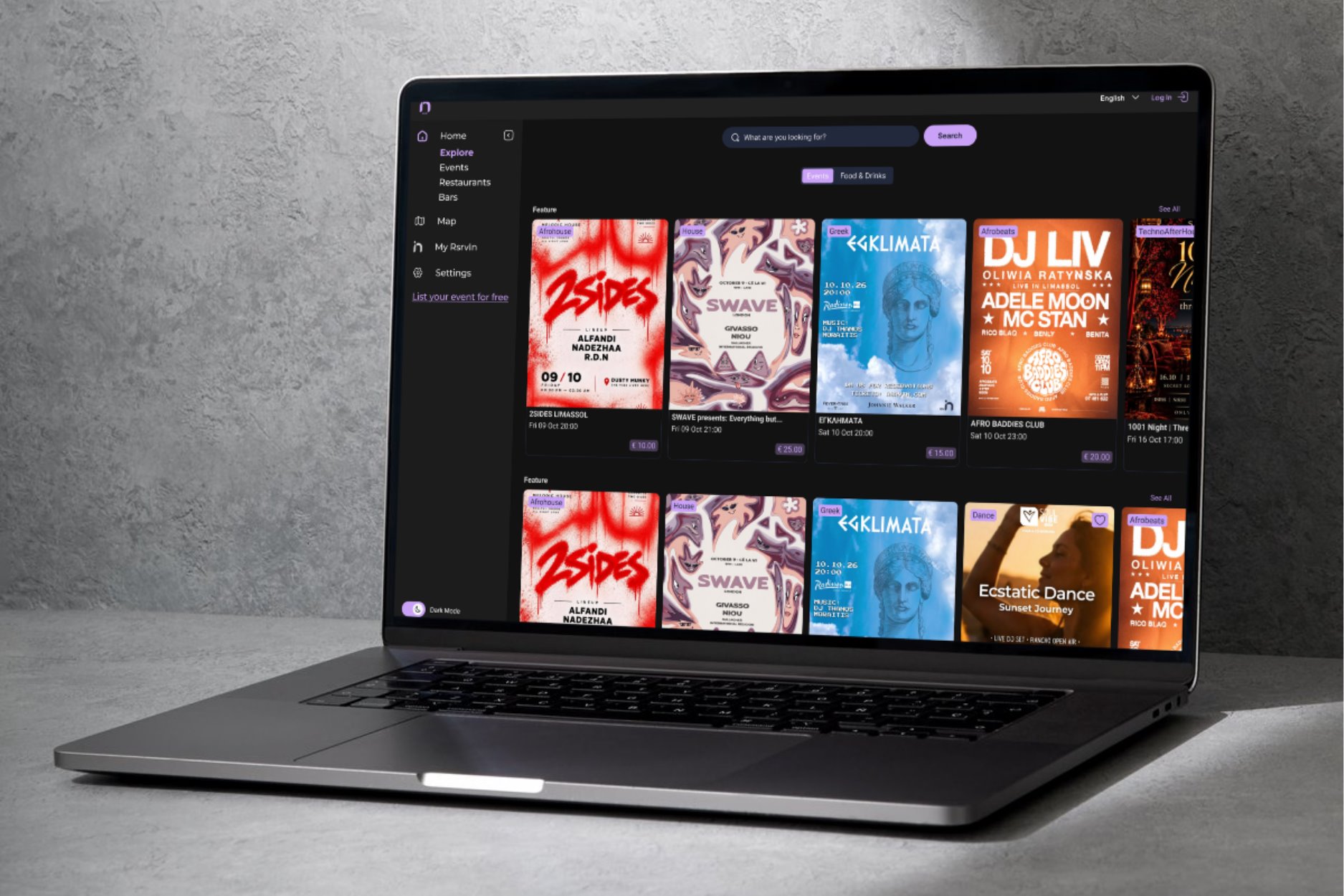 A laptop on a concrete surface showing the RsrvIn web app in dark mode: the Explore page with a sidebar, a search bar, Events and Food & Drinks tabs, and rows of poster-led event cards with genre tags, dates and prices